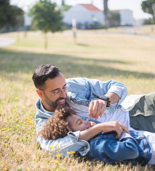 Man smiling and stretching outdoors in a park on a sunny day.